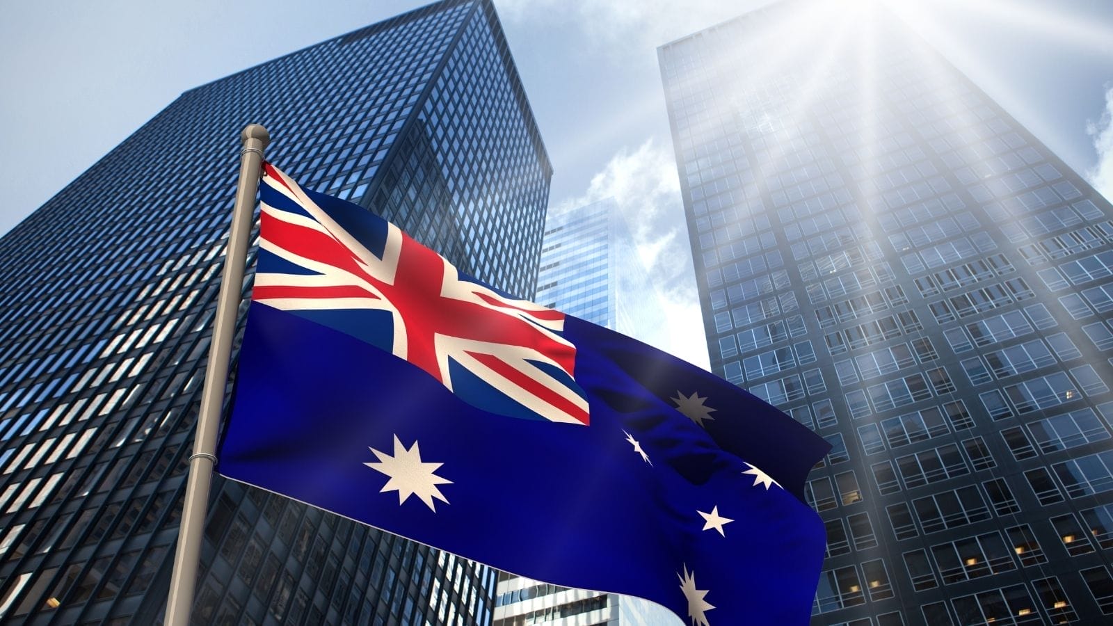 Two glass skyscrapers reaching a clear blue sky. In front of them, the Australian flag.