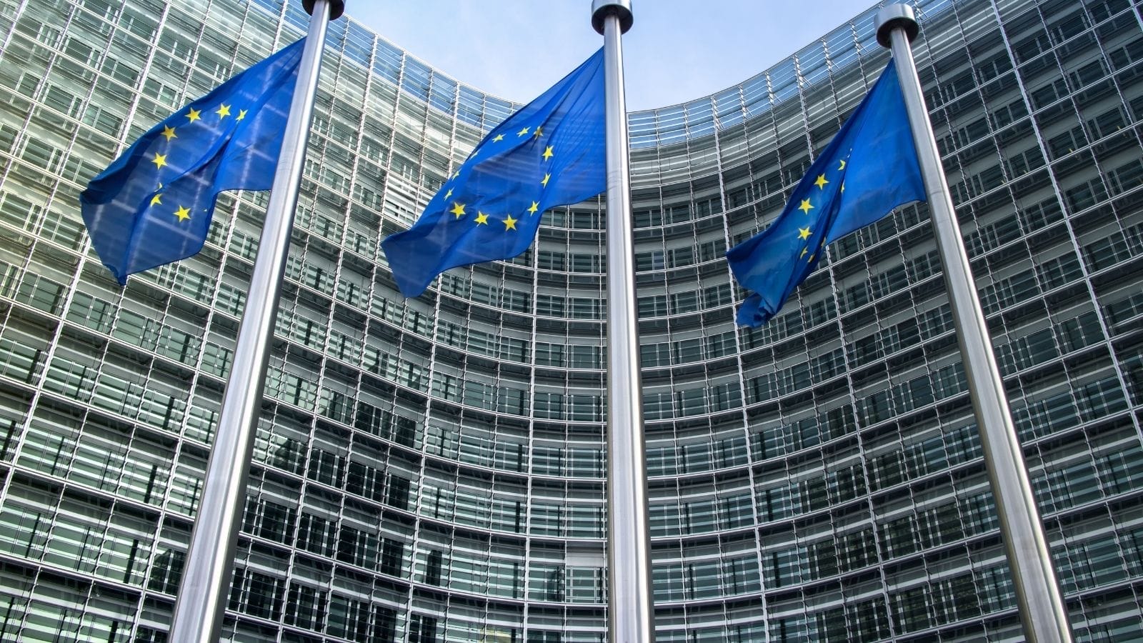 Three EU flags in front of the European Commission building.