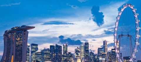 Skyline of Singapore at night with the Marina Bay Sands Hotel on the left and a ferris wheel on the right.