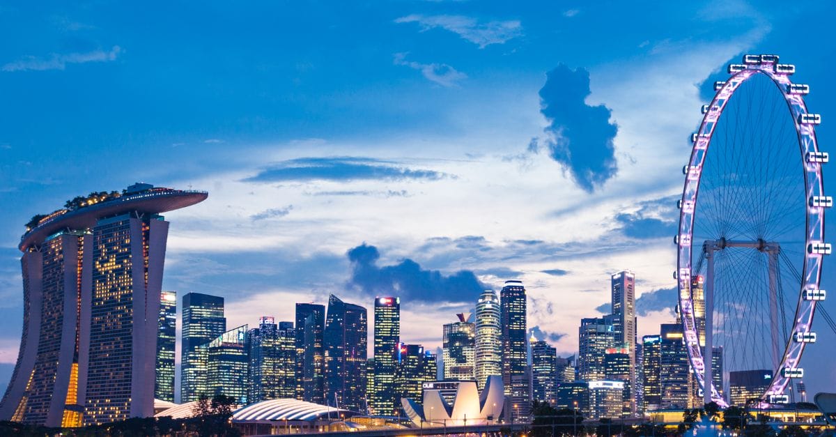 Skyline of Singapore at night with the Marina Bay Sands Hotel on the left and a ferris wheel on the right.