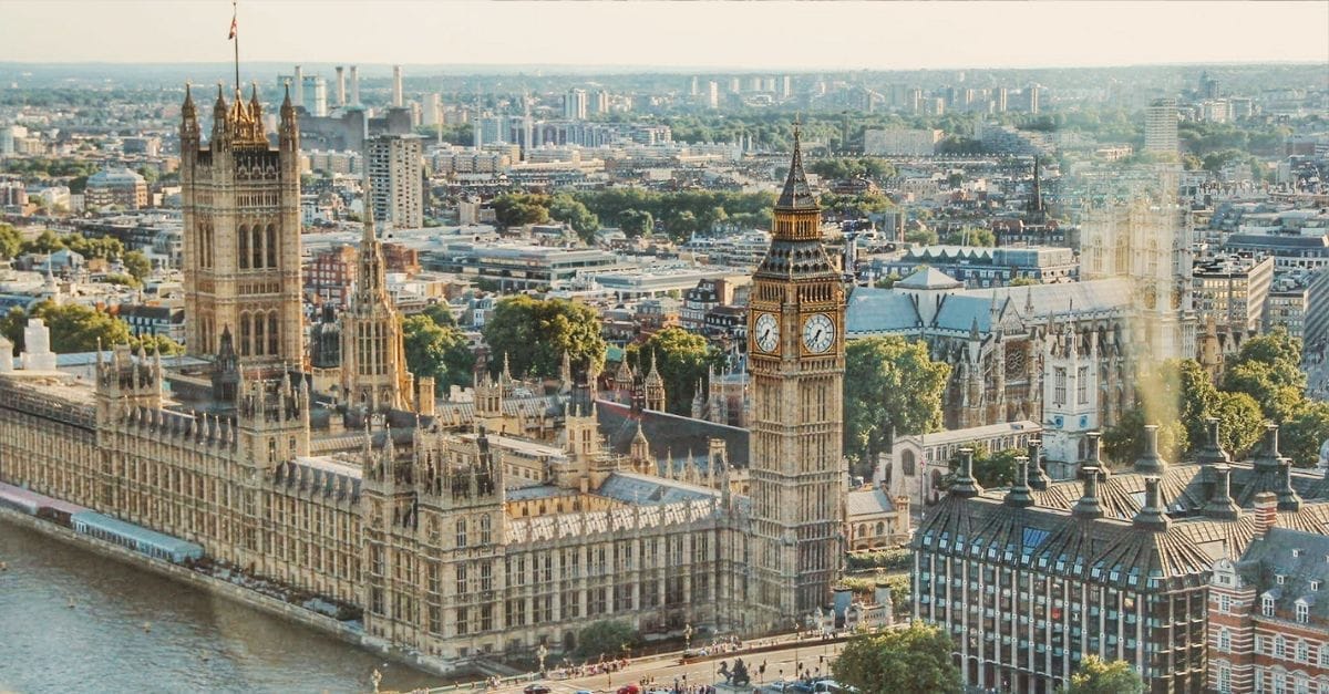 Sky view of the Parliament of the UK with Big Ben on the right-hand side and the river Thames below.