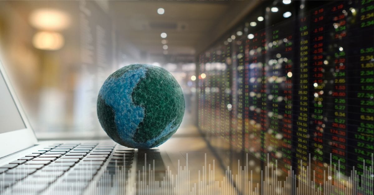 A globe of the world sitting on a laptopkeyboard. In the background, a data center.