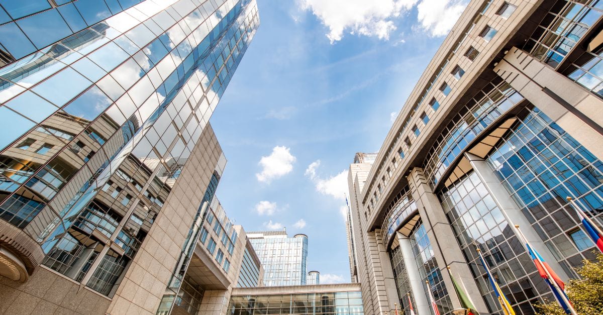 Upward view of the European Parliament, glass buildings against a blue sky with few clouds