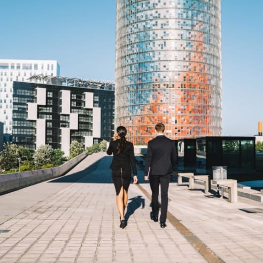 Managers walking down a street in a business district, surrounded by skyscrapers